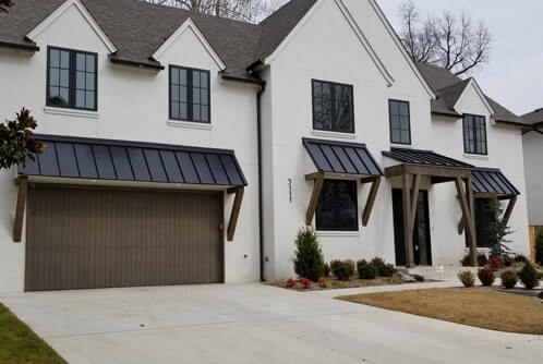 A white house with multiple Standing Seam Roofs